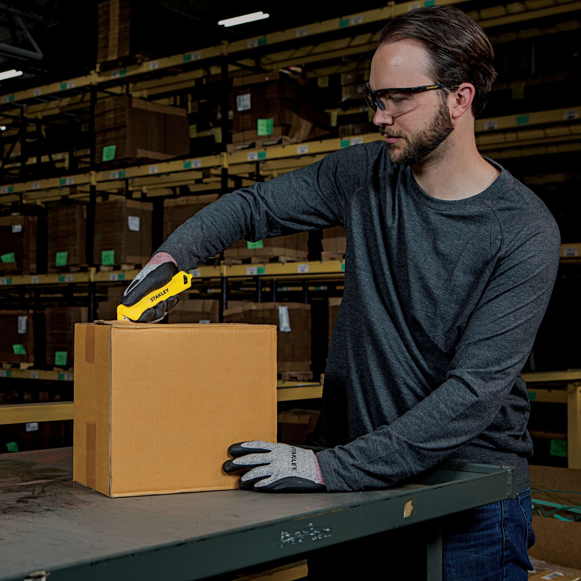 Single Sided Pull Cutter being used for opening cardboard box by person.