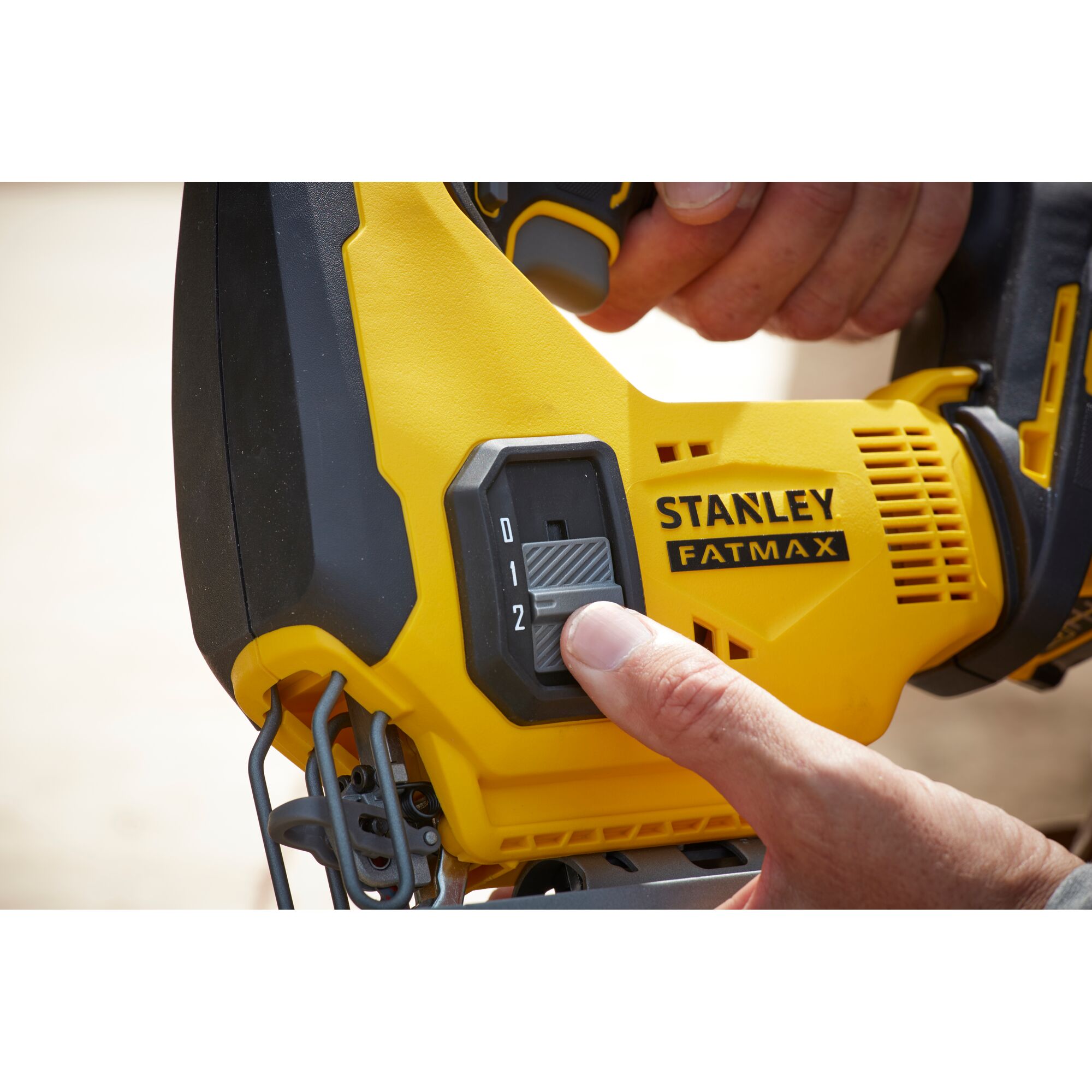 STANLEY SCJ600B jigsaw speed control switch close-up, yellow and black housing, photography of hand adjusting.