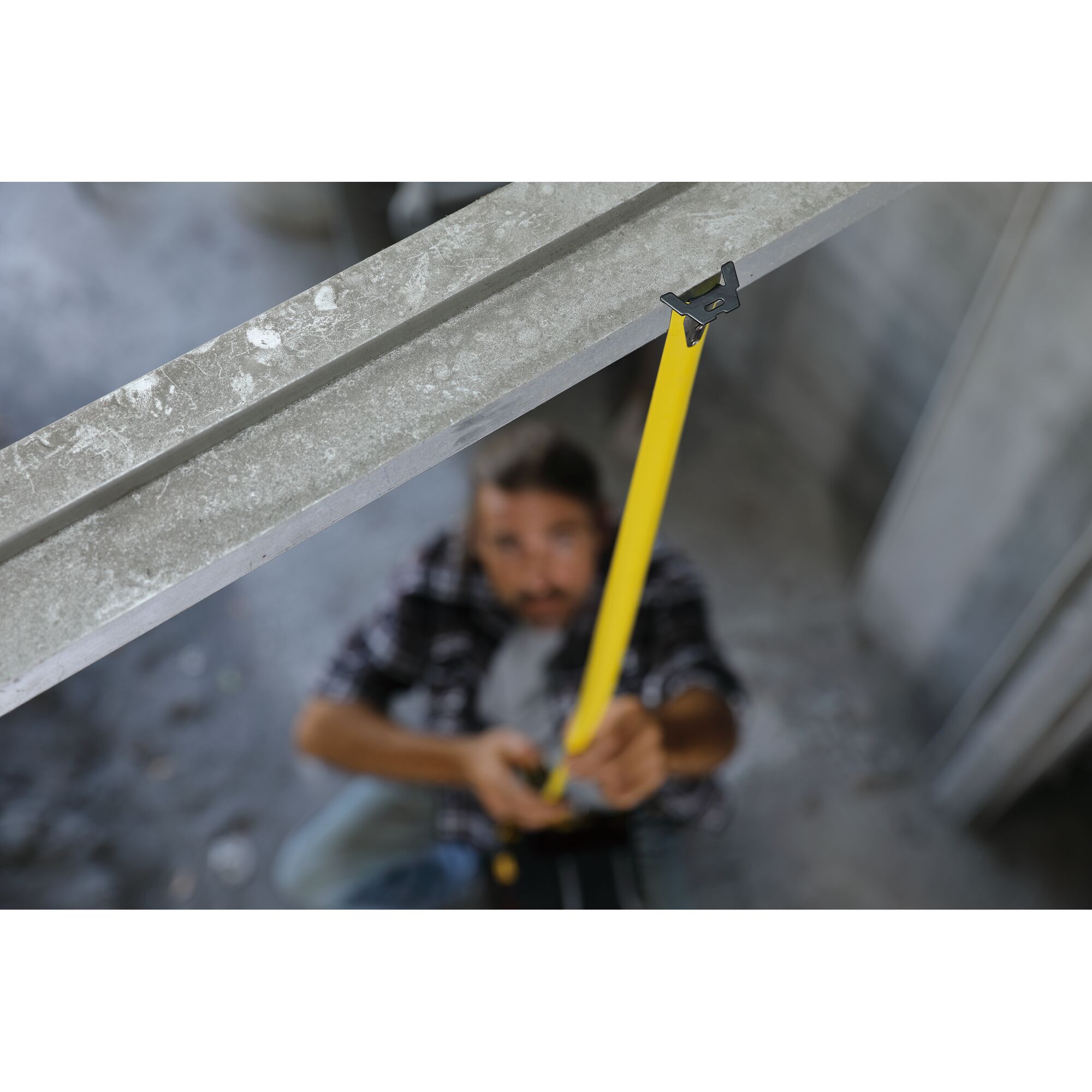 STANLEY STHT36195 tape measure extended from metal beam in construction setting, yellow color.