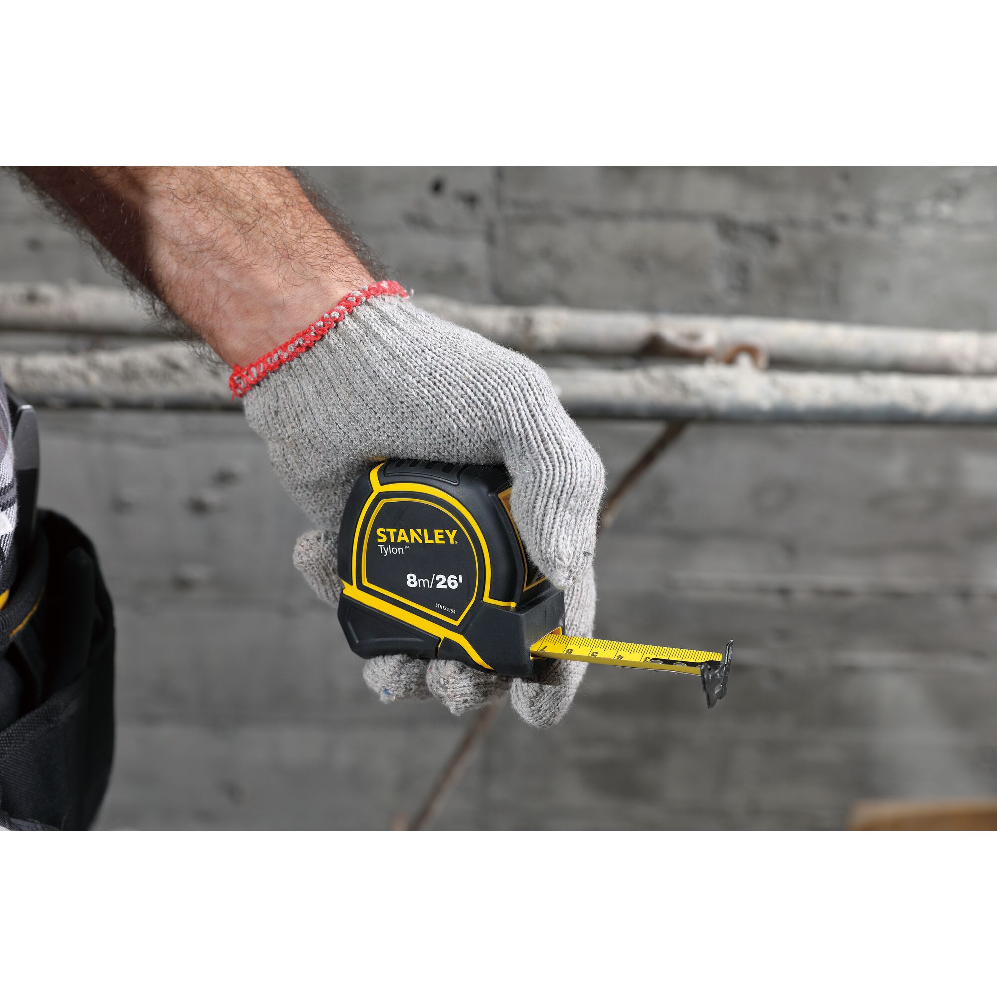 Photo of a gloved hand holding a STANLEY STHT36195 tape measure, yellow and black, partially extended.