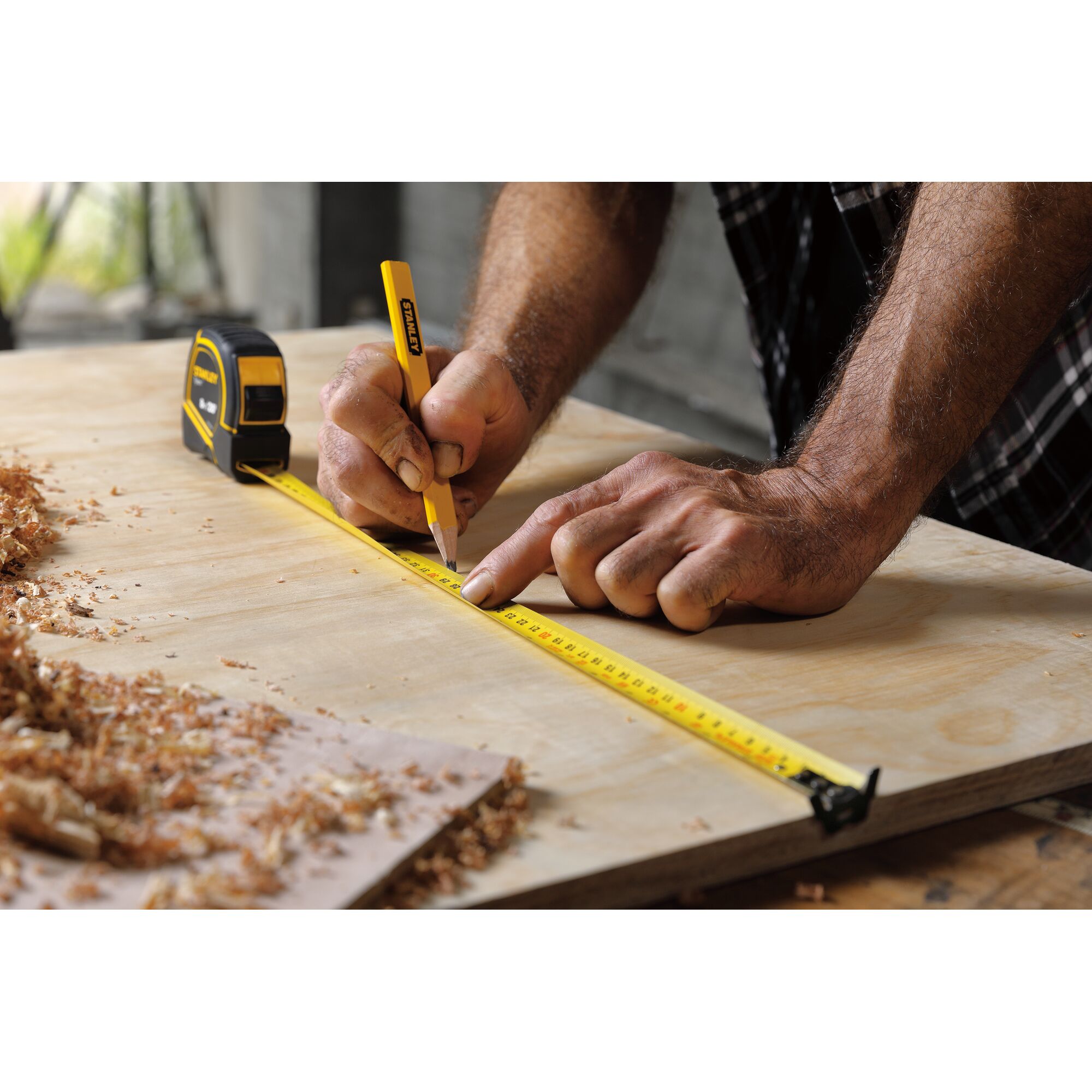 Stanley STHT36195 tape measure and pencil marking wood during carpentry work, close-up angle.