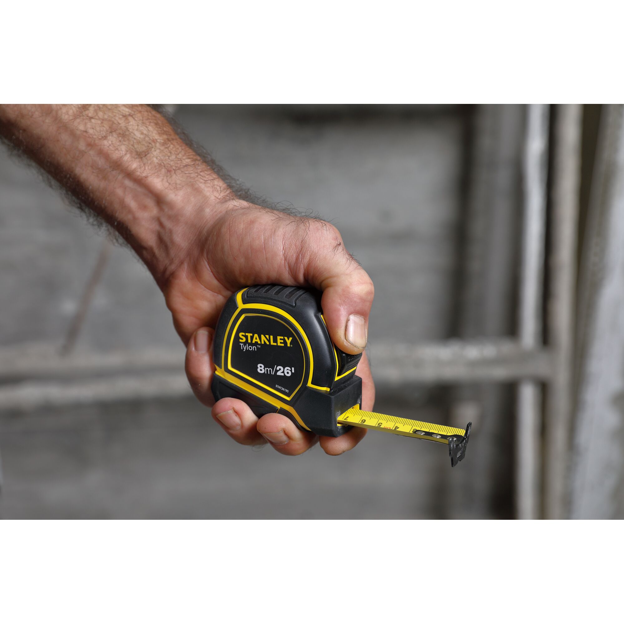 Photo of STANLEY STHT36195 tape measure held in hand, yellow and black, 8m/26ft, measuring tool.