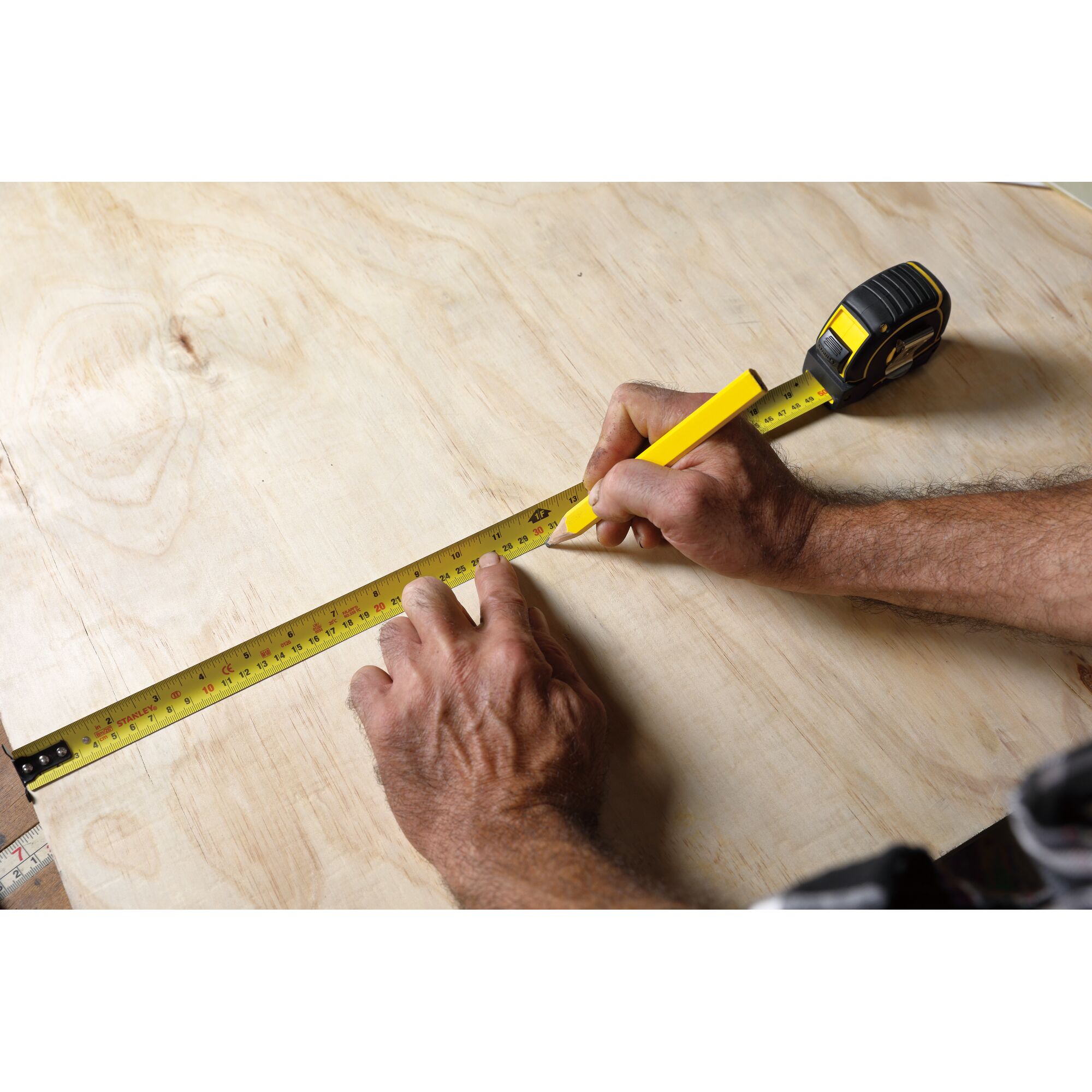 STANLEY STHT36195 tape measure used for marking measurements on plywood, close-up angle.