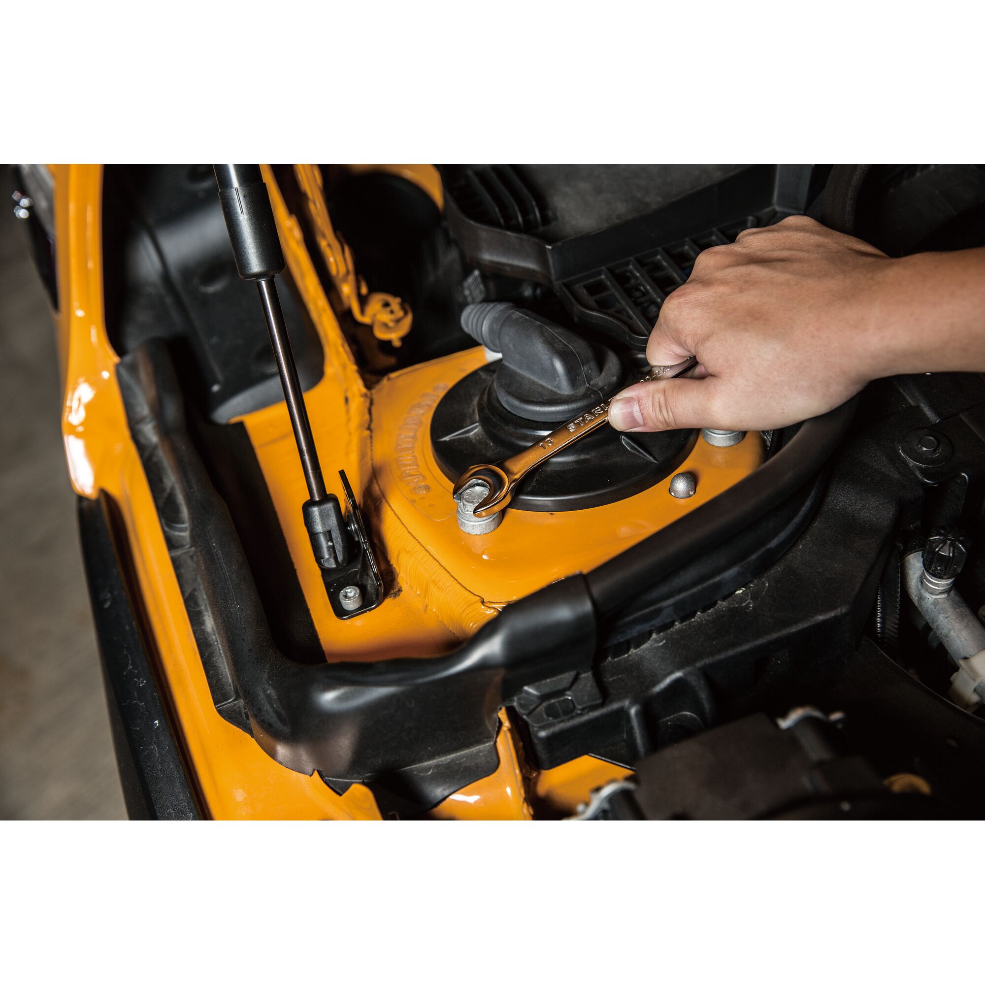 STANLEY STMT80223-8 ratcheting wrench used on orange engine part, close-up photo.