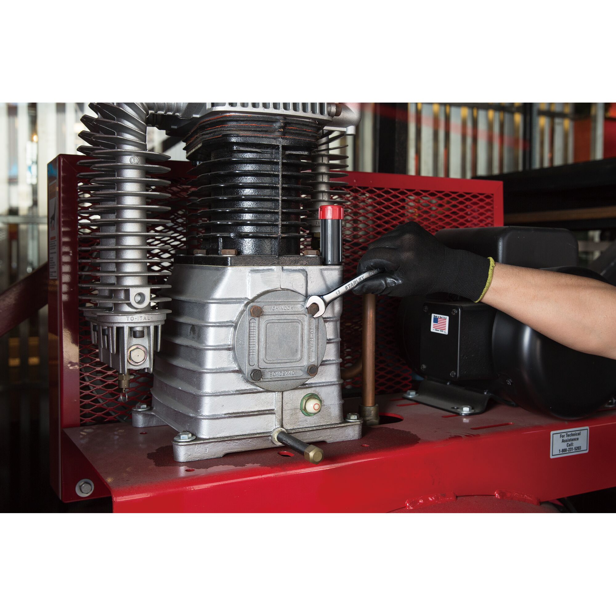 STANLEY STMT80223-8 wrench in use on air compressor, side angle, black glove holding tool.
